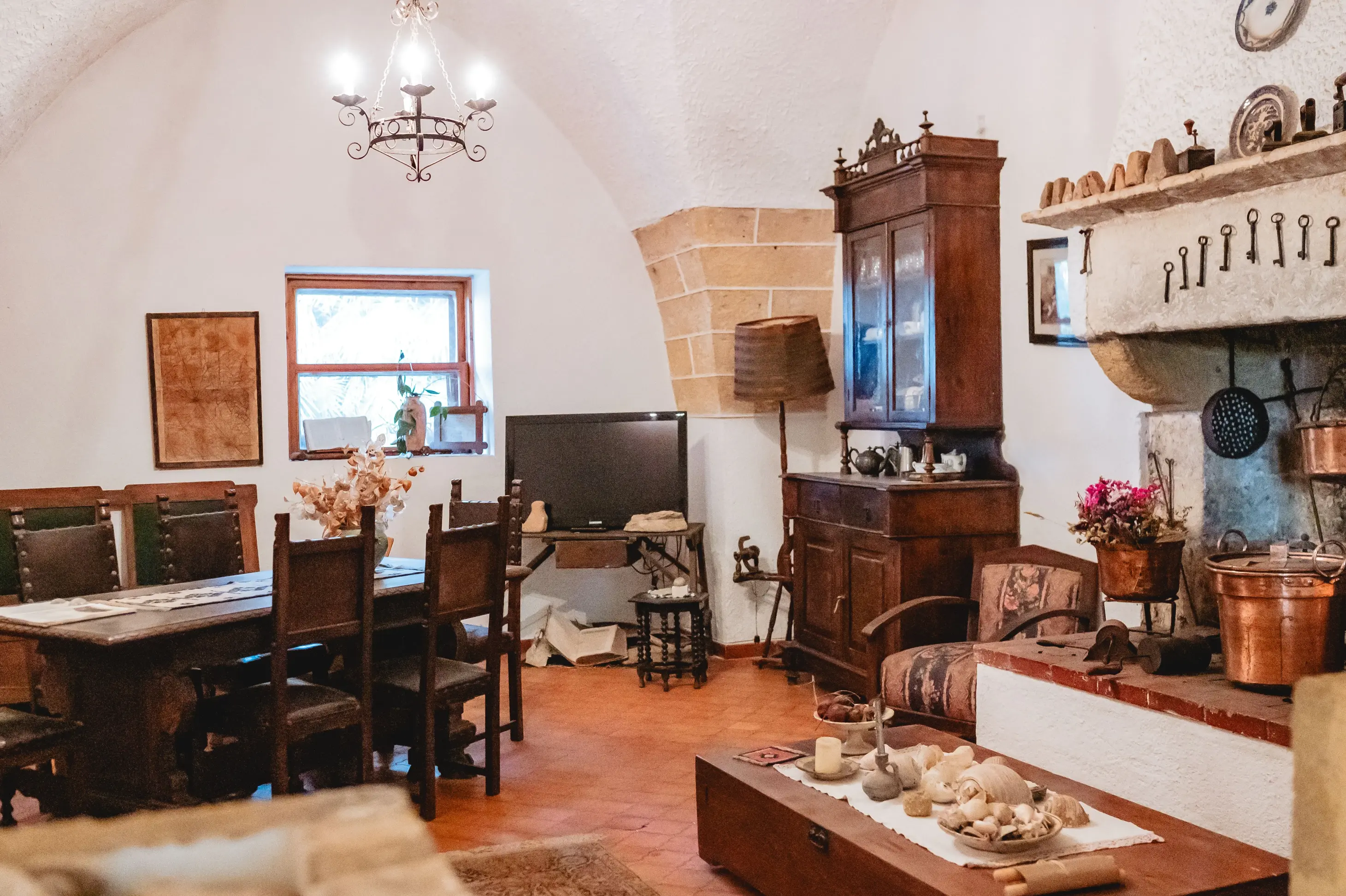 Dettaglio architettonico di una facciata in pietra con porta in legno scuro e vasi di fiori colorati, che riflette lo stile rurale e curato della struttura